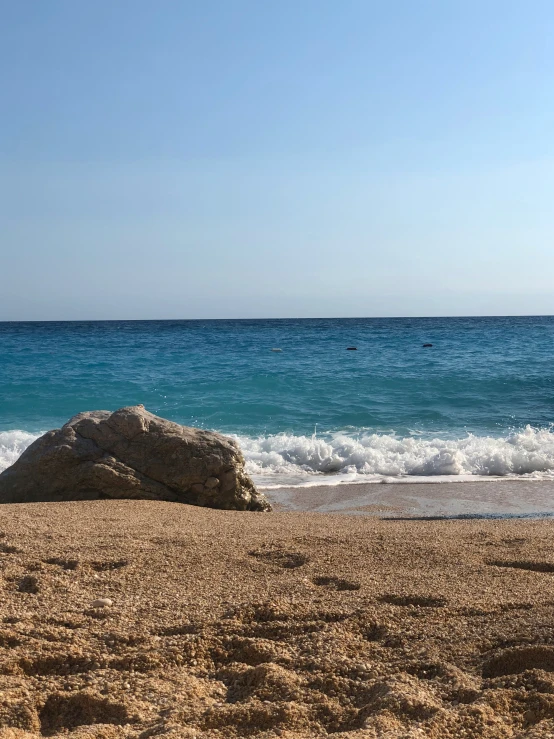 a big rock on the beach near the water