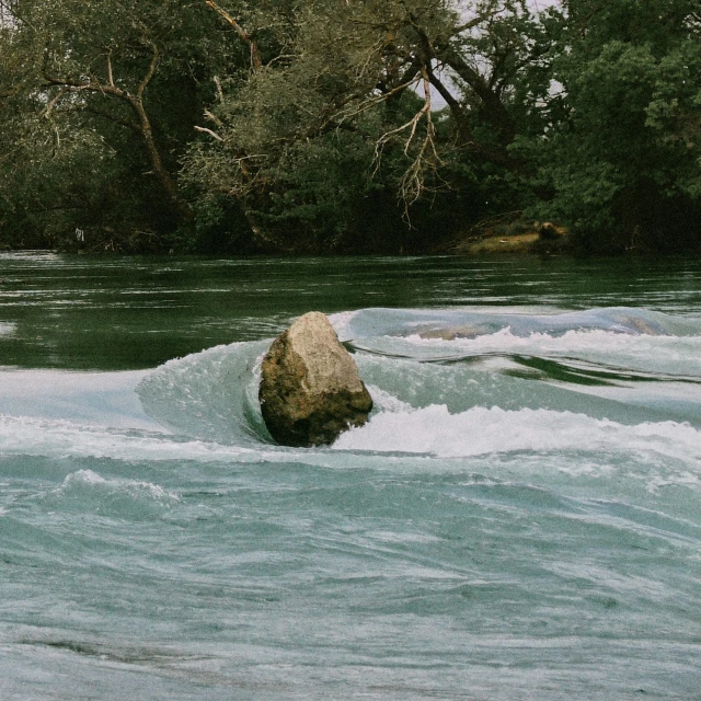 a large rock is in the middle of a rapid river