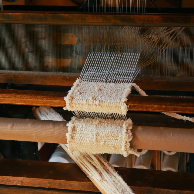 a long loom is weaving some fabric