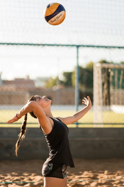 a woman is reaching for a volleyball while jumping into the air