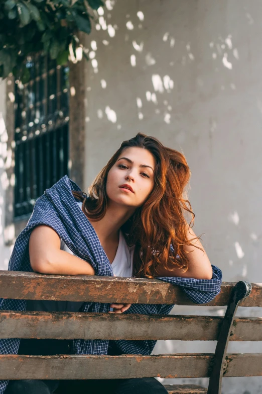 a woman in a striped shirt is sitting on a wooden bench