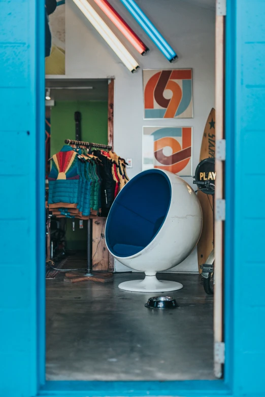 a blue wall with a white chair and surfboards behind it