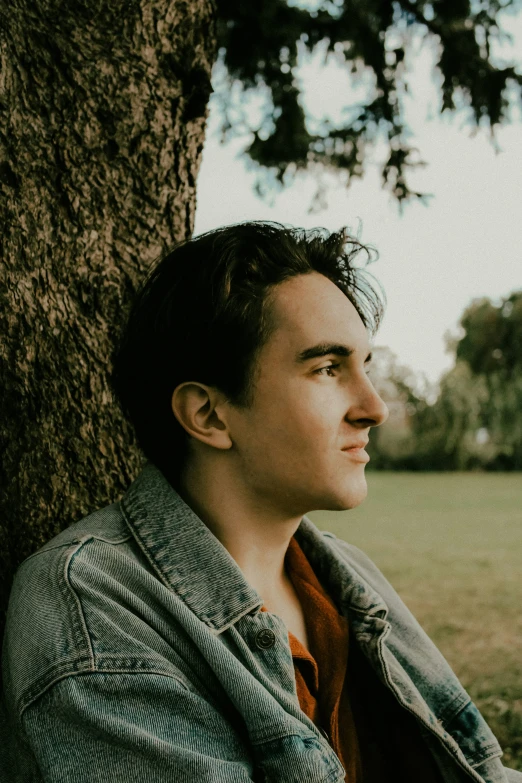 man sitting against tree with one eye open