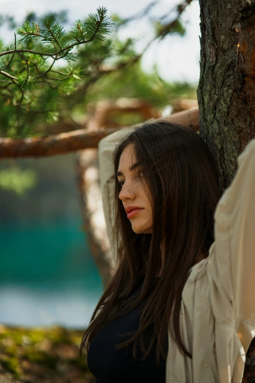 the girl is standing near a tree in the woods