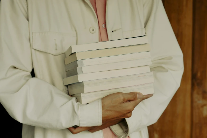 a man holding books and standing in front of wooden wall