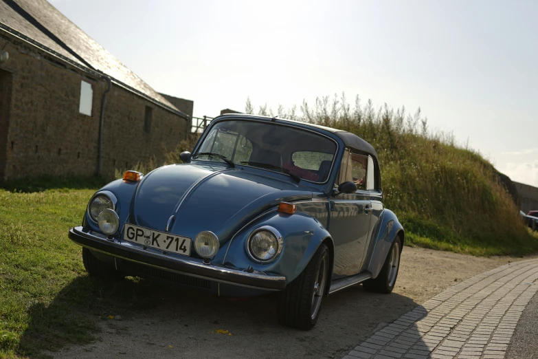 a blue classic car sitting on the side of a road
