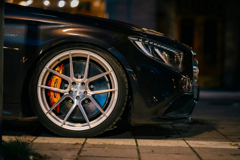 an mercedes wheel is shown at night, with bright lights reflected in the background