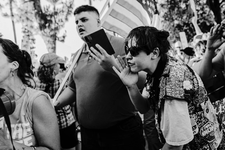 a group of people holding a book, waving american flags and making faces