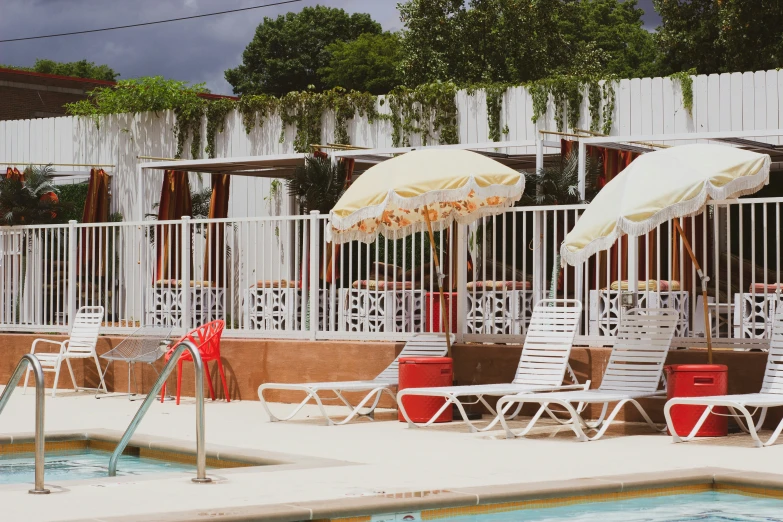 lounge chairs are near a pool while umbrellas are placed over