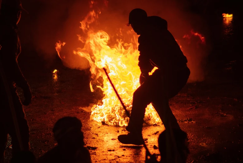 people standing in front of a fire with a broom