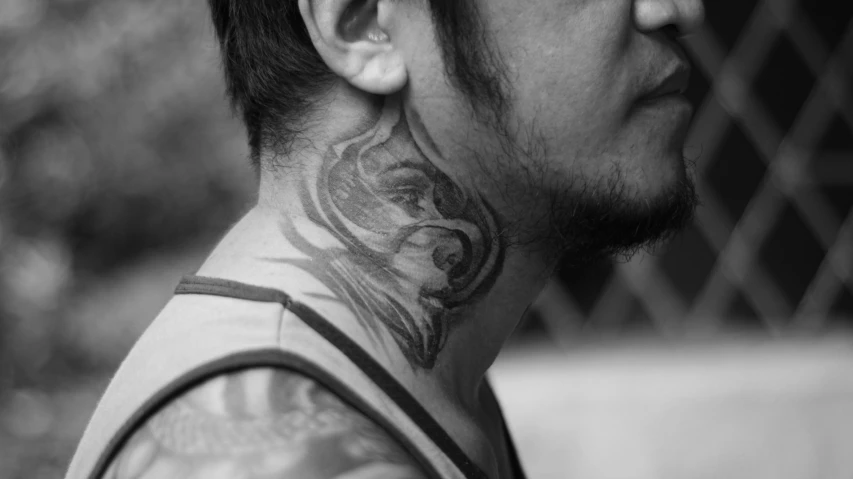 a man with a neck tattoo looking straight ahead