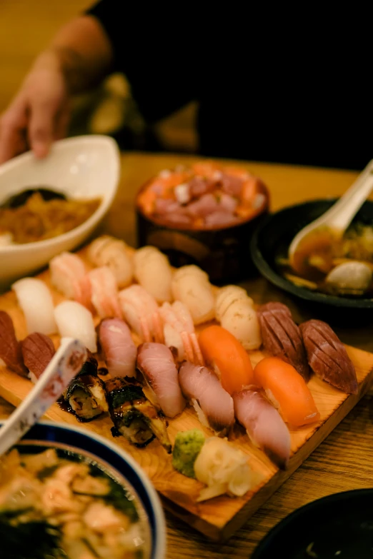 an assortment of sushi and noodles are on a board