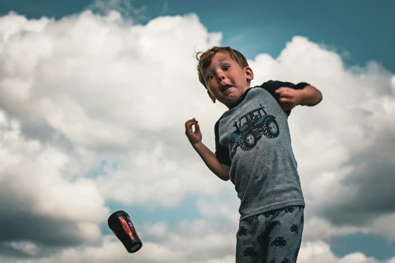 a boy is jumping up and running while looking at the camera