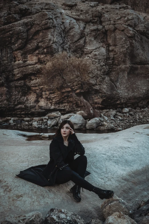 a young woman wearing black sitting on rocks