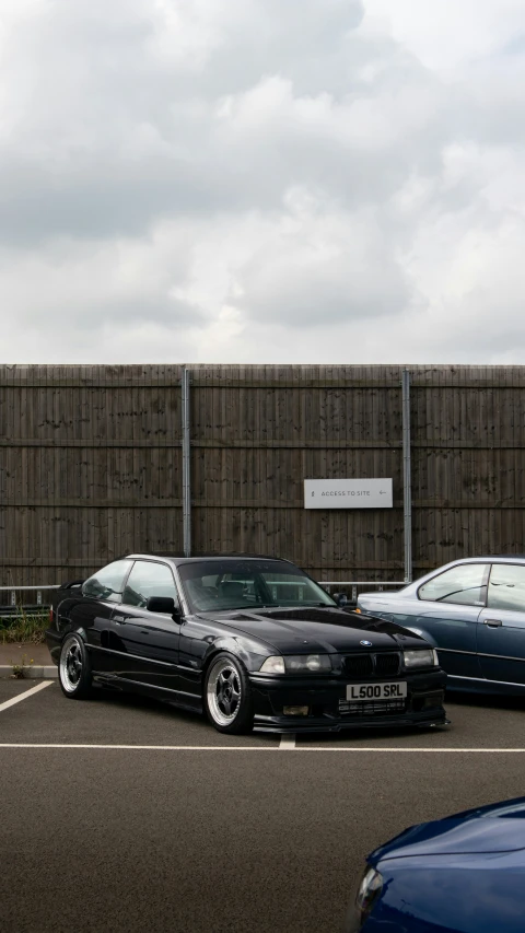 three cars sitting in a parking lot next to a wall