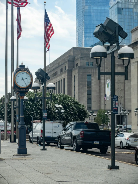 cars drive down a busy city street with a clock