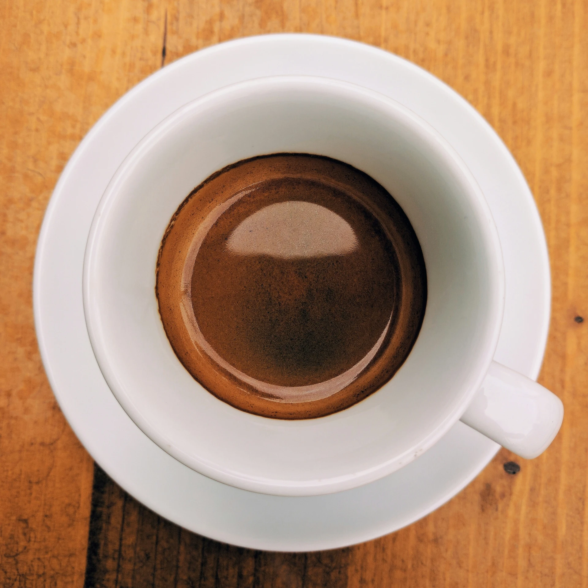 the top view of a cup of coffee that is on a wooden table