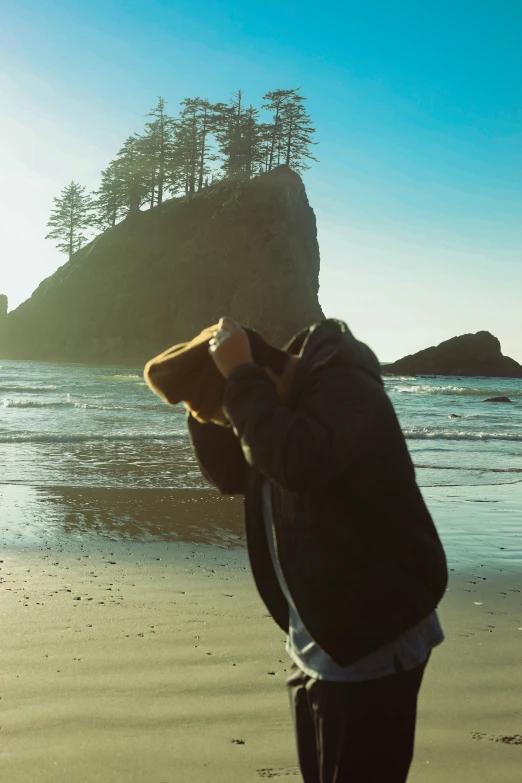 man wearing hat standing on beach looking at water