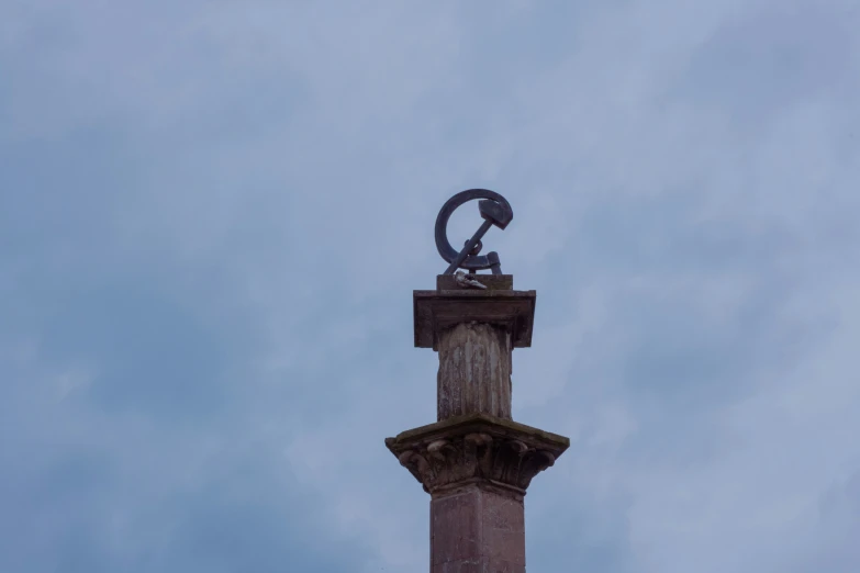 a statue with an object on it in the middle of the sky