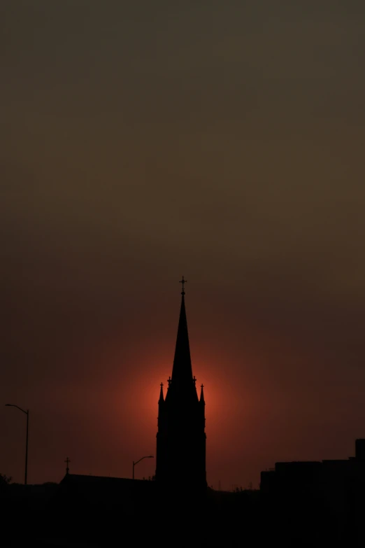 a picture of the setting sun behind a church steeple