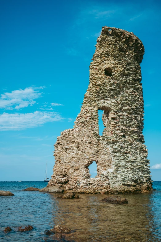 a tall tower next to the ocean with blue sky in the background