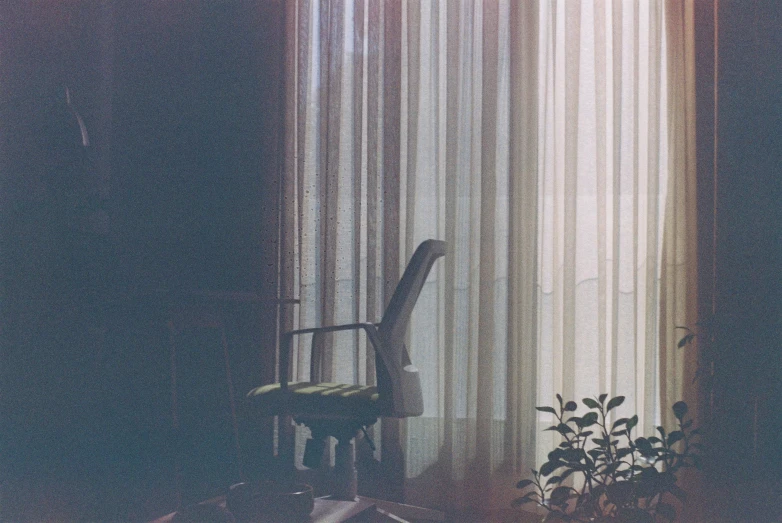 a chair and window behind curtains in a room