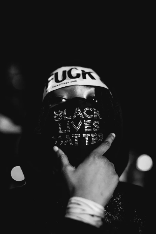 a person holding up a bottle with the words black lives here on it