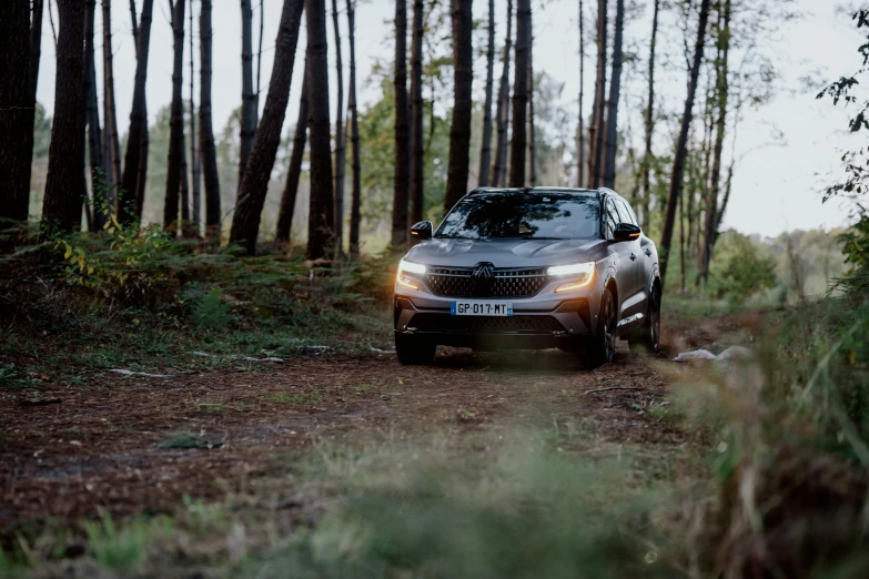 the front end of a silver four - door vehicle driving down a trail