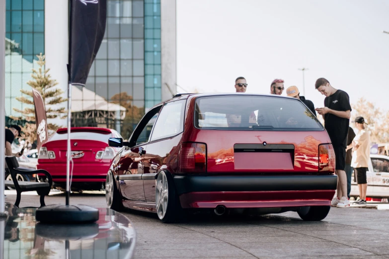 the group of people stand in front of a parked car