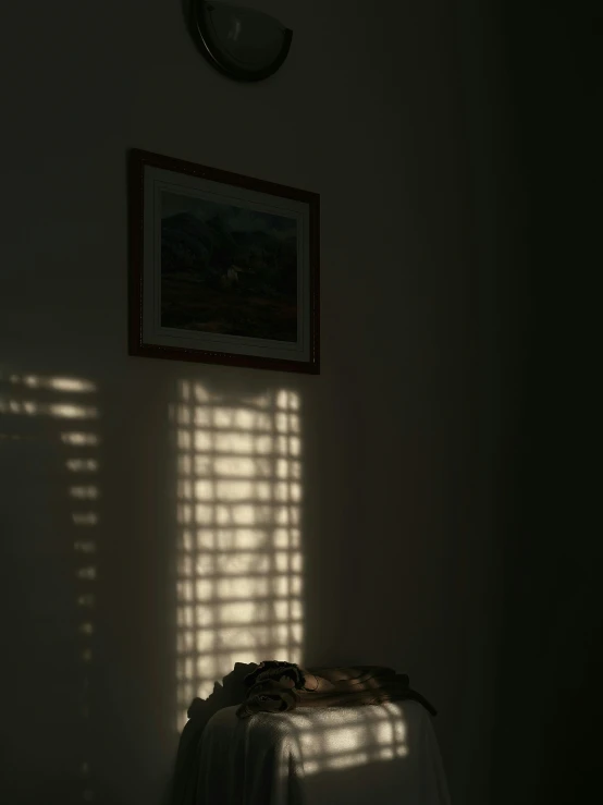 the shadows of a picture and a blanket cast onto the wall of a bedroom