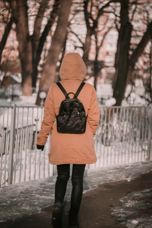 a woman walking along a road covered with snow