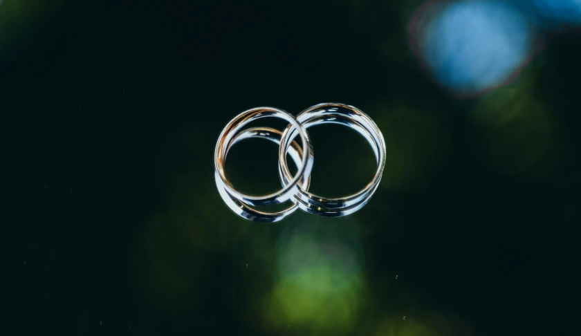 two silver wedding rings laying on top of each other