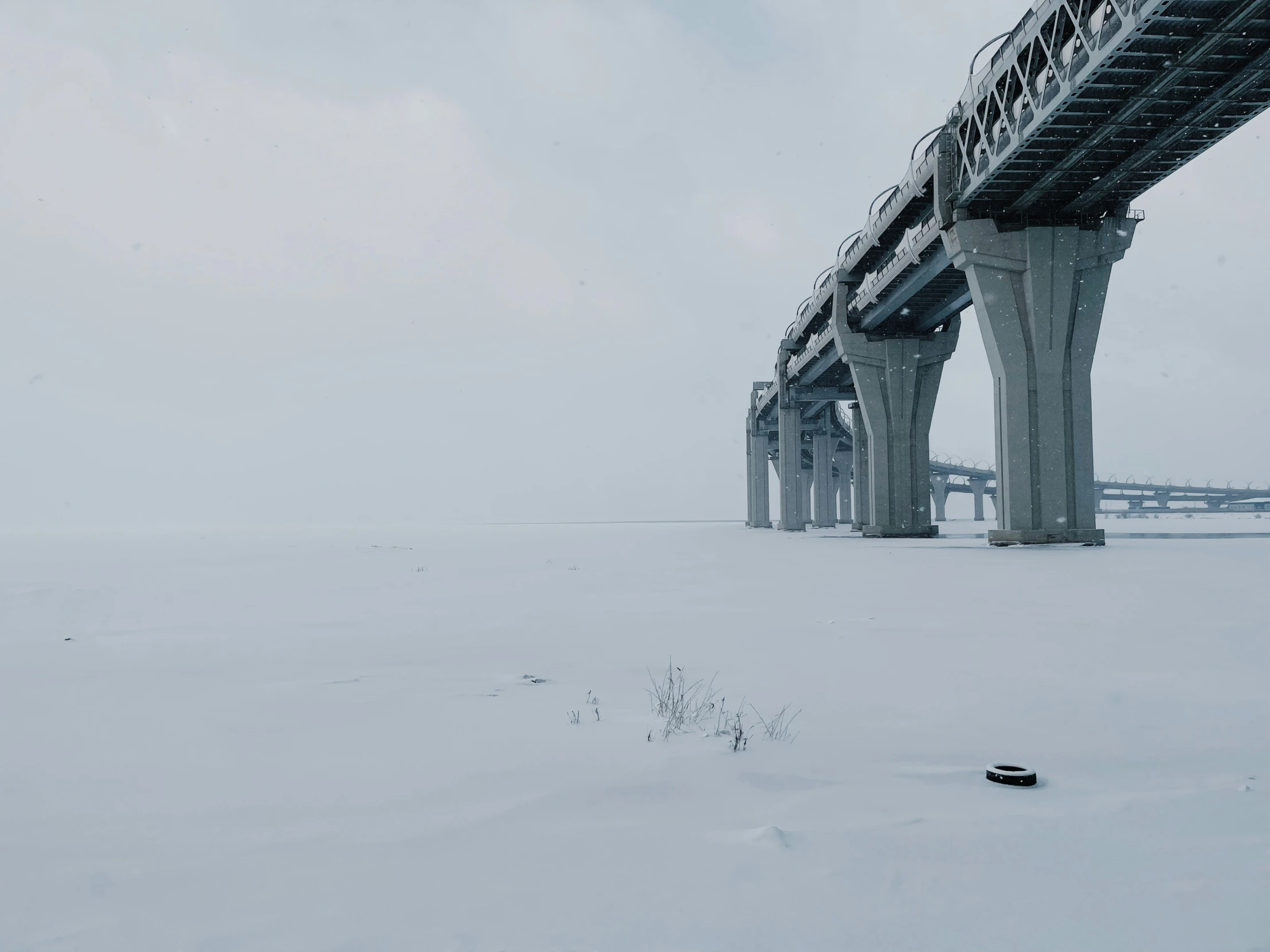 there is a long stretch of snow beneath a bridge