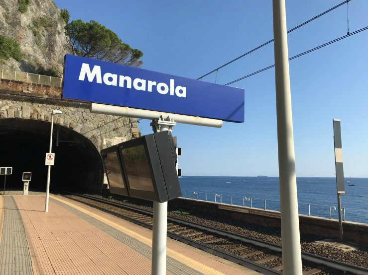 a blue sign that is above the train tracks