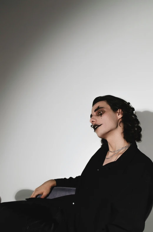 a woman is sitting in front of a wall with a fake mustache on her face