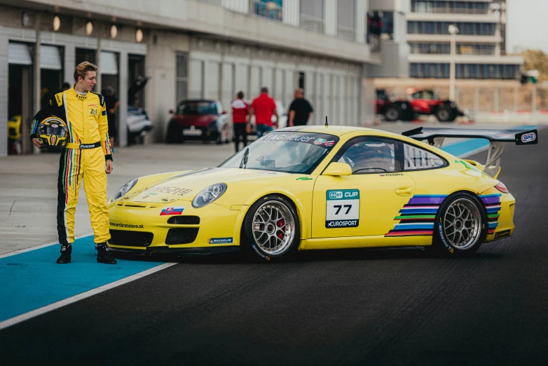 a man standing next to a yellow car with colorful stripes on it