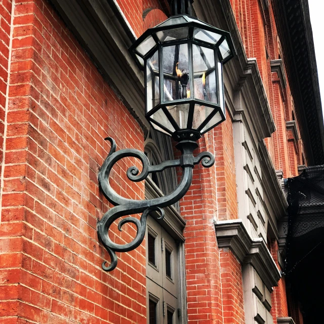 a light post mounted on the side of a brick building