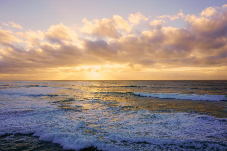 the sun sets on an ocean with large waves