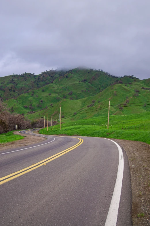 a road leads into a valley with a lush green hillside in the distance