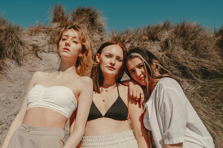 three women with their arms around each other standing in front of a grassy hillside