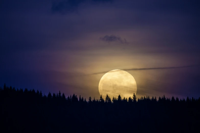 the moon shines brightly in the twilight sky