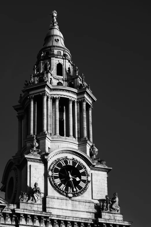 the clock tower has statues on top and arches around