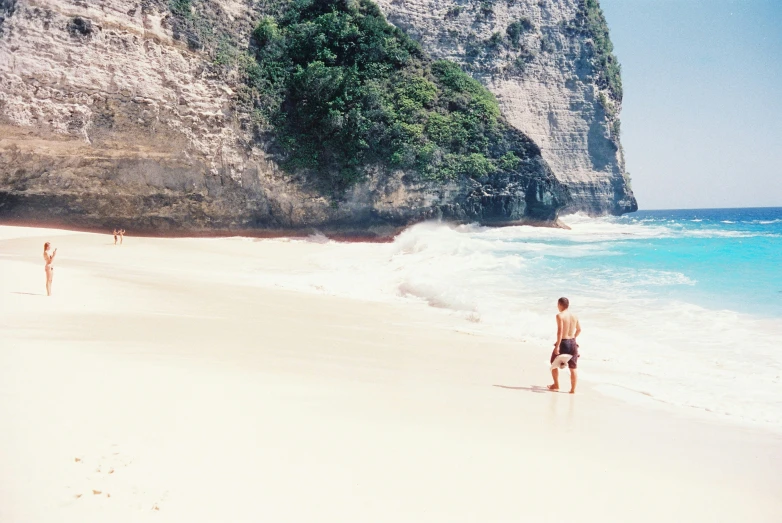 people walking along the beach during a sunny day