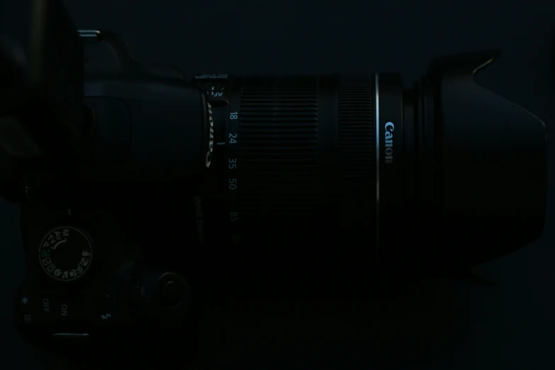 a black camera in the dark with a small lens attached