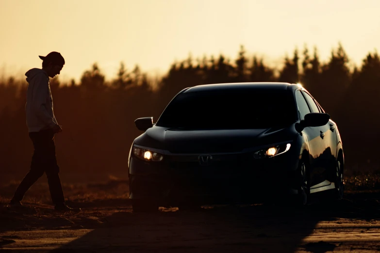 a man is standing by his car in the sunset