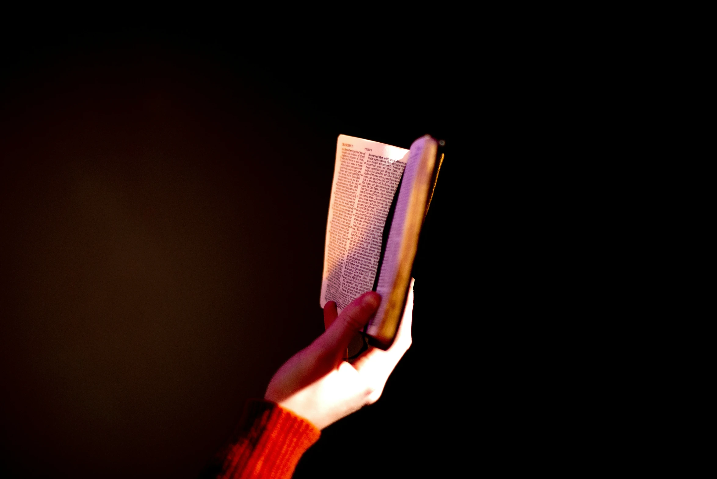 a person holding a book in the dark