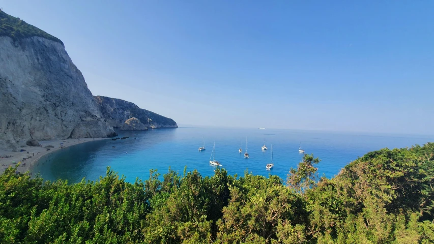 boats on the ocean off of a cliff in a sunny day