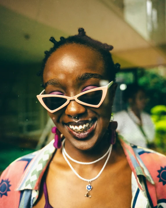 a woman smiling while wearing sunglasses and pearls