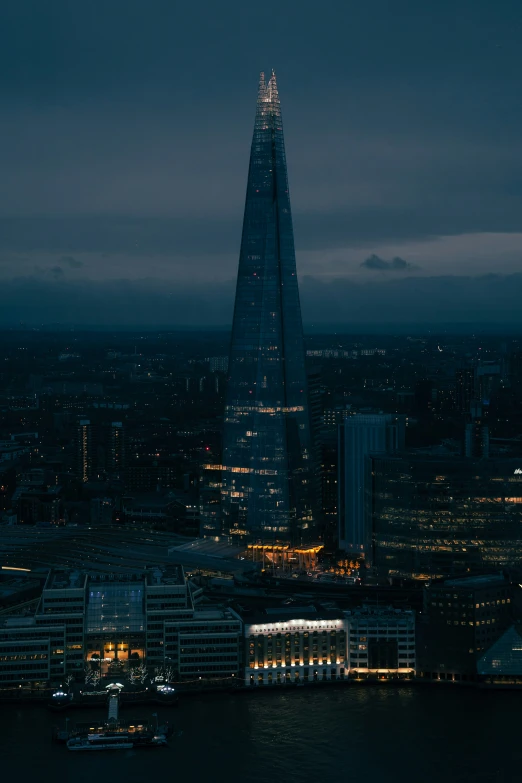 london's thames and shardle tower are lit up at night