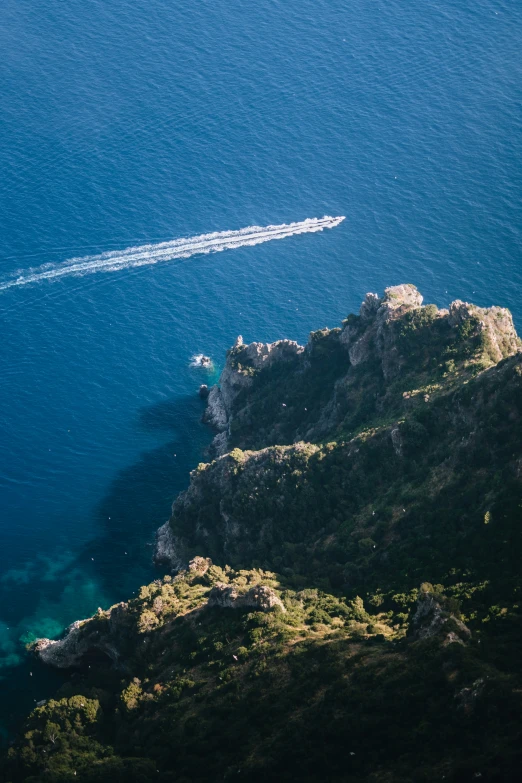a boat is heading into the water off a rocky cliff